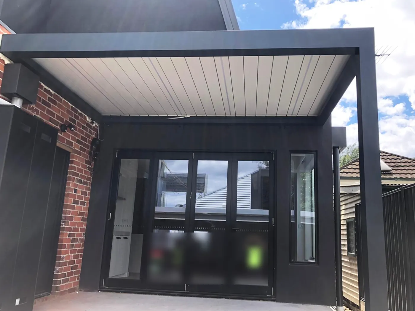 Pergola bioclimatique anthracite aux lames blanches, adossée