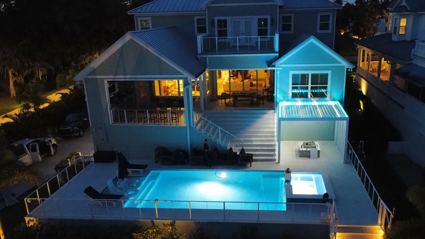 Pergola bioclimatique éclairée de nuit au bord d’une piscine