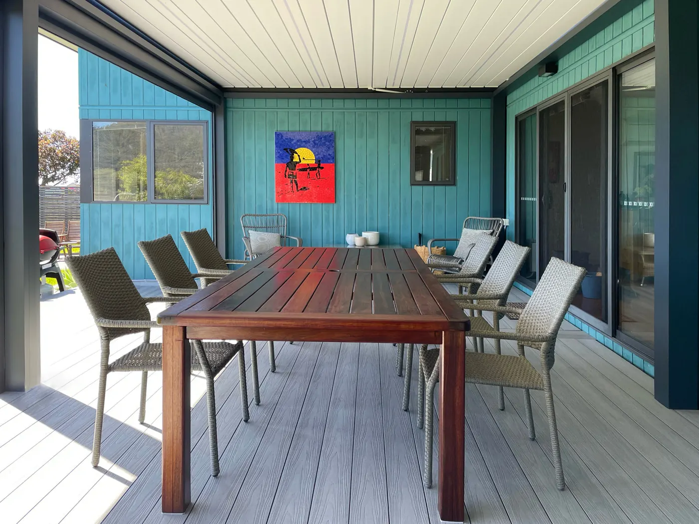 Table de jardin sous une pergola bioclimatique aux lames blanches