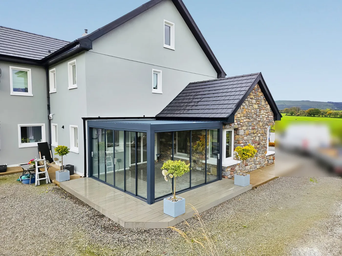 Pergola bioclimatique vitrée contre une maison en pierre