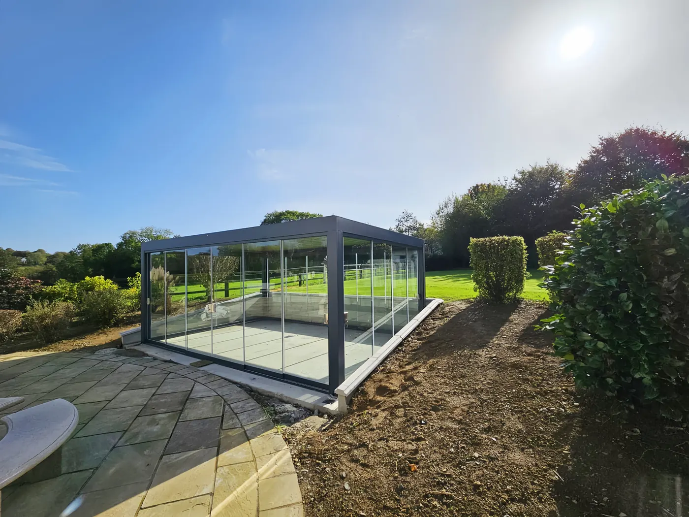 Pergola bioclimatique vitrée au milieu d’un jardin