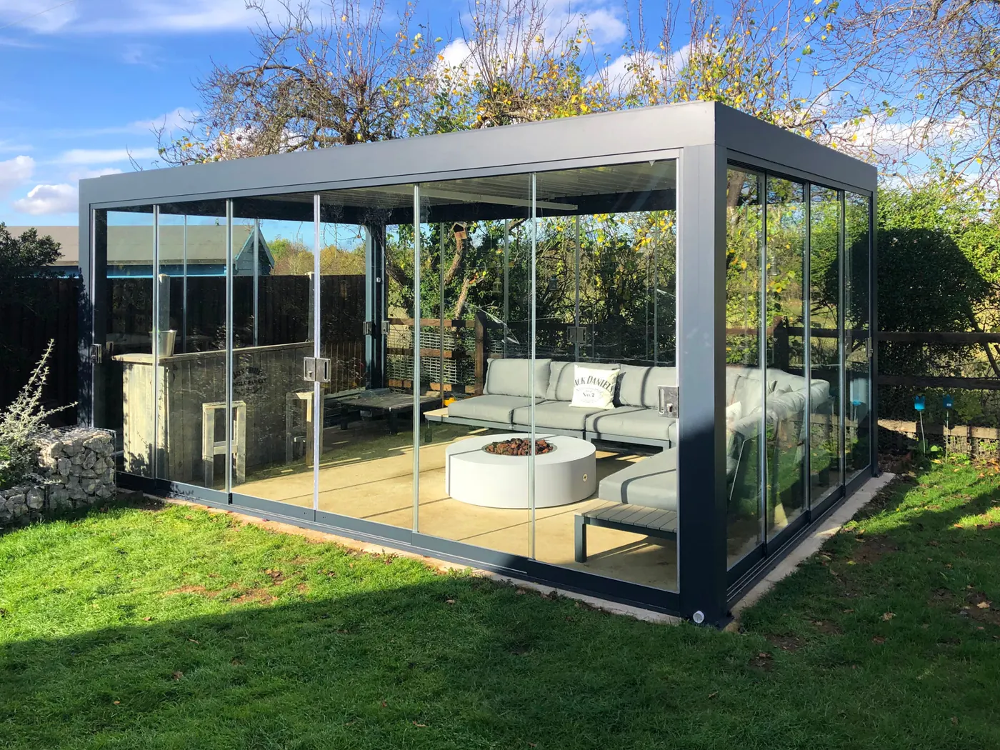 Pergola bioclimatique entièrement vitrée, salon de jardin et brasero