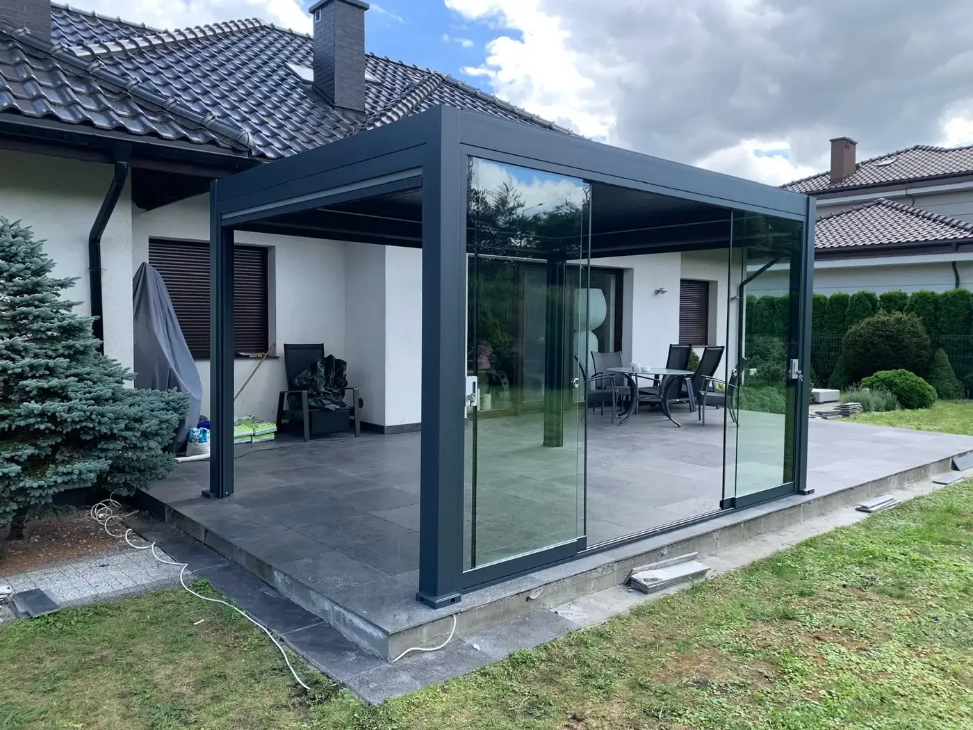 Pergola bioclimatique avec vitres coulissantes sur une terrasse carrelée