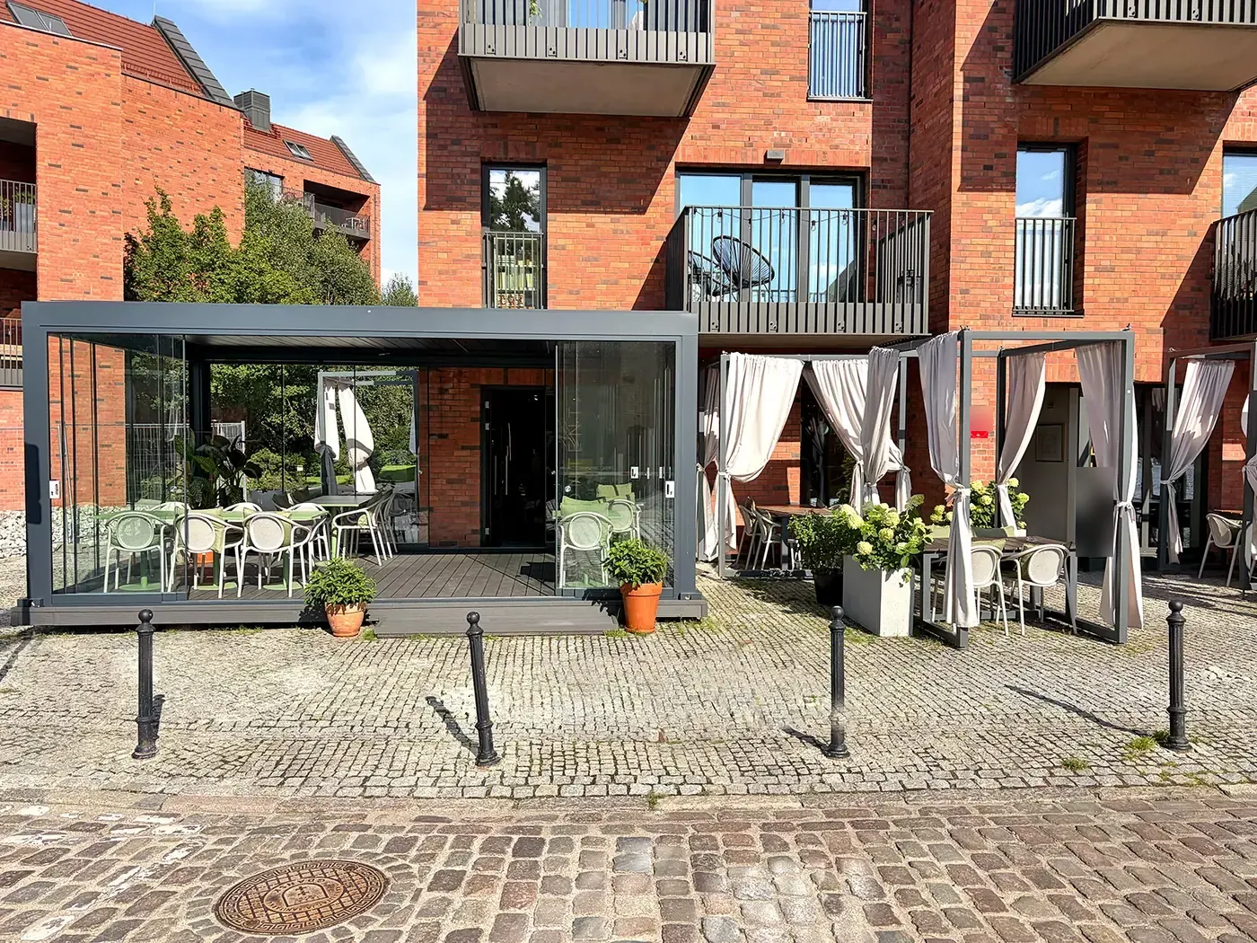 Vue d'ensemble d'une terrasse de restaurant sous une pergola bioclimatique vitrée