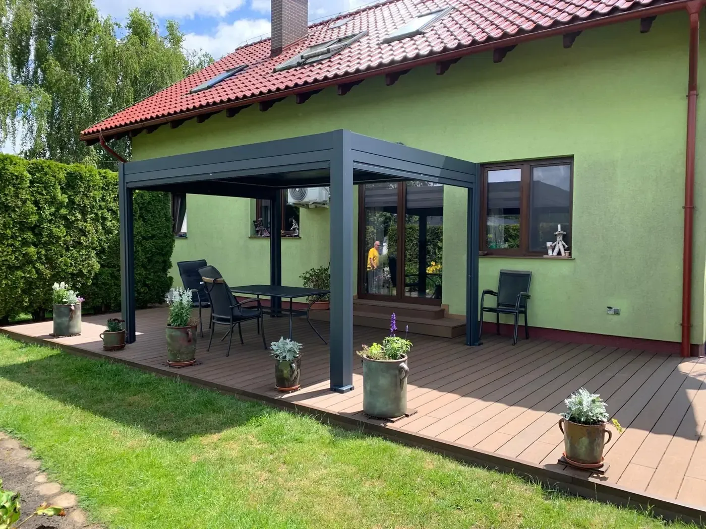Pergola bioclimatique adossée sur une terrasse en bois